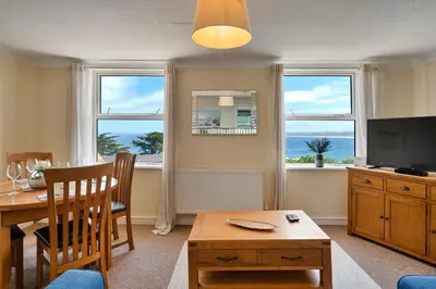 a living room with a table and a television and two windows at Finest Retreats - No 11 Porthminster in St Ives