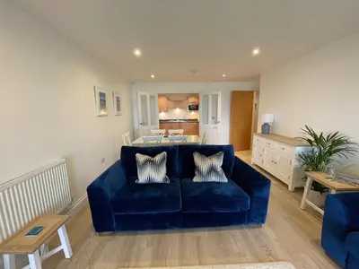 a living room with a blue couch and a kitchen at 30 Bredon Court at Fistral Beach Newquay in Newquay
