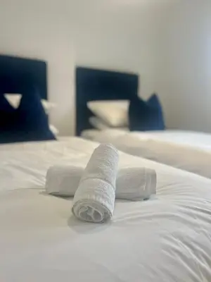 two rolled towels on top of a white bed at 30 Bredon Court at Fistral Beach Newquay in Newquay