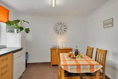 a kitchen with a table and a clock on the wall at Finest Retreats - Number 10 Porthmeor in St Ives