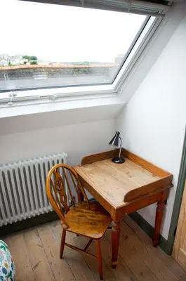 a wooden table and a chair in a room with a window at Wellington House Boutique Holiday Let in Falmouth
