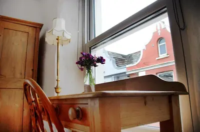 a table with a vase of flowers on it next to a window at Wellington House Boutique Holiday Let in Falmouth