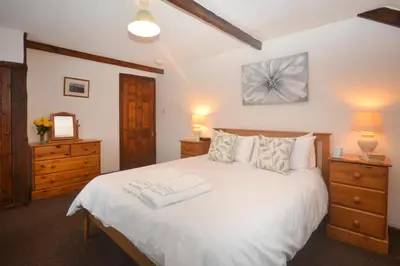 a bedroom with a large white bed with two dressers at 2 Bed in St. Merryn oc-w29716 in St Merryn