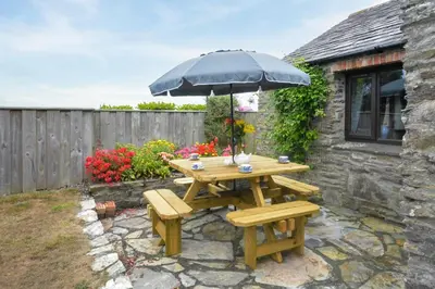 a wooden picnic table with an umbrella and two benches at 2 Bed in Padstow oc-w3658 in St Merryn