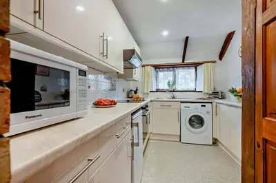 a kitchen with white cabinets and a washer and dryer at 2 Bed in Padstow oc-w3658 in St Merryn