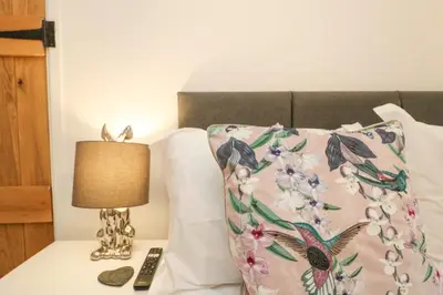 a bed with a pillow and a lamp on a table at Bumblebee Cottage in Bodmin