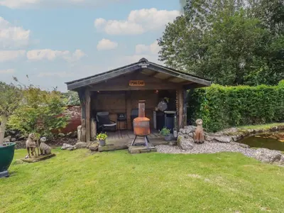 a small shed in a yard next to a pond at Bumblebee Cottage in Bodmin