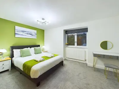 a bedroom with a bed with a green wall at Bredon Court by Signature Stays - Modern - Beach - Parking in Newquay