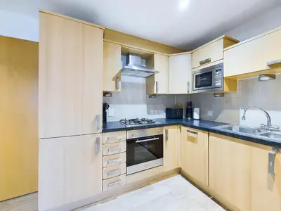 a kitchen with wooden cabinets and a stove top oven at Bredon Court by Signature Stays - Modern - Beach - Parking in Newquay
