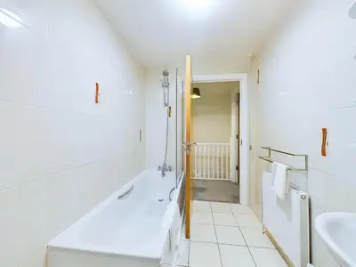 a white bathroom with a tub and a sink at Bredon Court by Signature Stays - Modern - Beach - Parking in Newquay