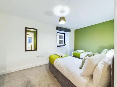 a bedroom with two beds and a mirror at Bredon Court by Signature Stays - Modern - Beach - Parking in Newquay