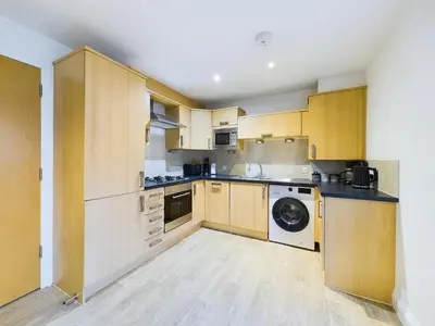 a kitchen with wooden cabinets and a washer and dryer at Bredon Court by Signature Stays - Modern - Beach - Parking in Newquay