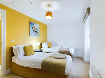 two beds in a room with yellow walls at Newquay Beach House by Signature Stays - Parking - Modern - Coastal in Newquay