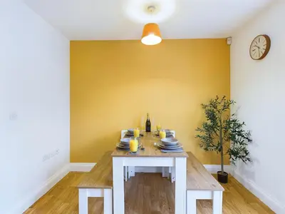 a dining room with a table and a yellow wall at Newquay Beach House by Signature Stays - Parking - Modern - Coastal in Newquay