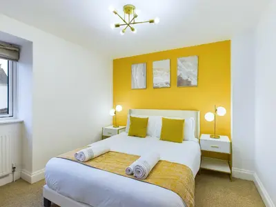 a bedroom with a large white bed with yellow walls at Newquay Beach House by Signature Stays - Parking - Modern - Coastal in Newquay