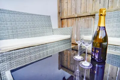 a bottle of champagne and two wine glasses on a table at Newquay Beach House by Signature Stays - Parking - Modern - Coastal in Newquay