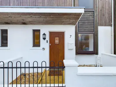 a white house with a wooden door and a fence at Newquay Beach House by Signature Stays - Parking - Modern - Coastal in Newquay