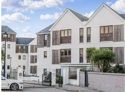 a white apartment building with a car parked in front at Newquay Beach House by Signature Stays - Parking - Modern - Coastal in Newquay