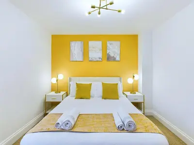 a bedroom with a large white bed with yellow walls at Newquay Beach House by Signature Stays - Parking - Modern - Coastal in Newquay