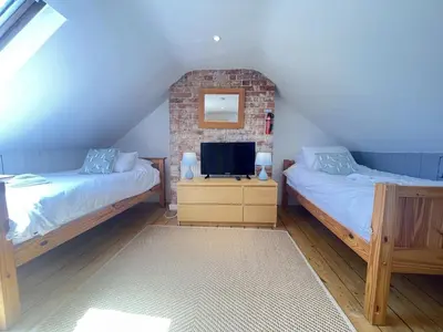a bedroom with two beds and a tv on a dresser at Mermaids Rest in St Ives