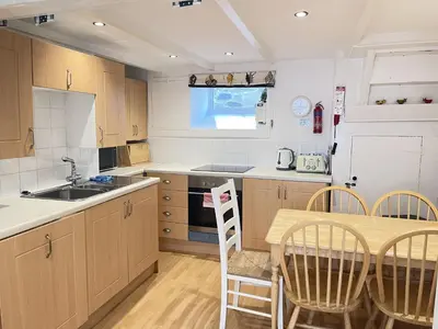 a kitchen with a wooden table and a table and chairs at Mermaids Rest in St Ives