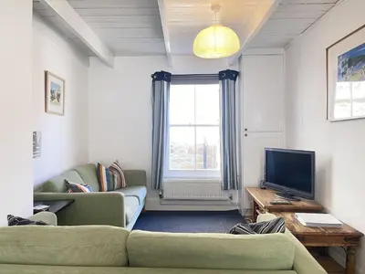 a living room with a couch and a television at Mermaids Rest in St Ives