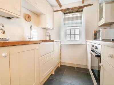 a kitchen with white cabinets and a window at Aunt Dora's in Port Isaac