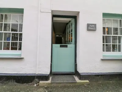 a white building with a green door and a sign at Aunt Dora's in Port Isaac