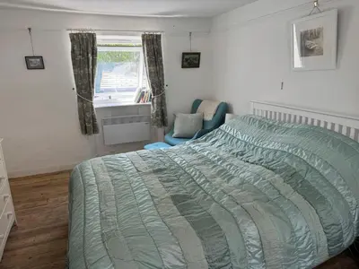 a bedroom with a bed and a chair and a sink at Seaforth - Fisherman's Cottage in Gorran Haven