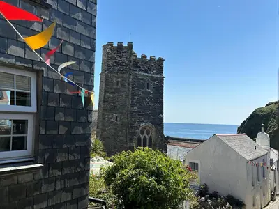 a building with flags on it next to the ocean at Seaforth - Fisherman's Cottage in Gorran Haven