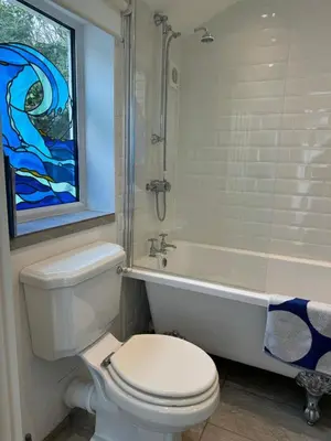 a bathroom with a toilet and a tub and a window at Seaforth - Fisherman's Cottage in Gorran Haven