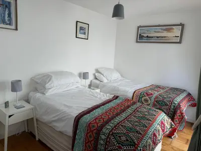 a bedroom with two beds and a table with a night stand at Seaforth - Fisherman's Cottage in Gorran Haven