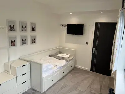 a white bedroom with a bed and a tv at Art Deco 52 in Truro