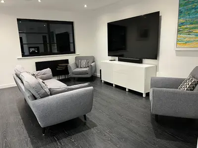 a living room with two chairs and a flat screen tv at Art Deco 52 in Truro