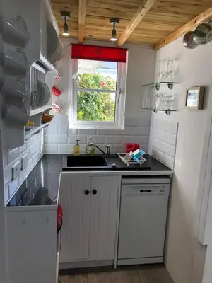a white kitchen with a sink and a window at The Nook in Padstow
