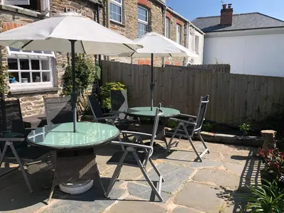 two tables and chairs with umbrellas on a patio at The Nook in Padstow