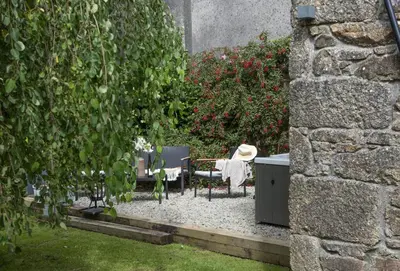 a garden with chairs and a table and some bushes at The Hay Loft in Camborne