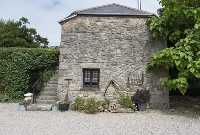 a stone building with stairs and a window at The Hay Loft in Camborne