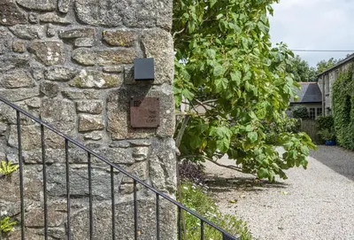 a stone wall with a fence next to a gate at The Hay Loft in Camborne