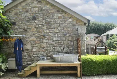 a bath tub sitting on a table next to a stone wall at The Hay Loft in Camborne