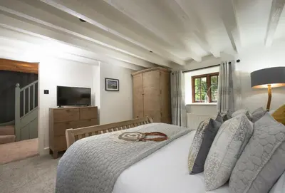 a bedroom with a white bed with a wooden headboard at The Hay Loft in Camborne