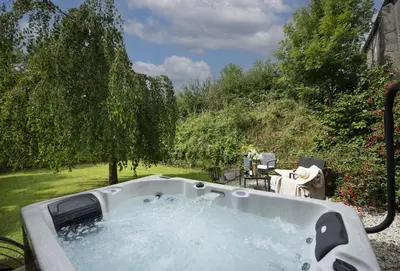 a jacuzzi tub in a yard with trees at The Hay Loft in Camborne