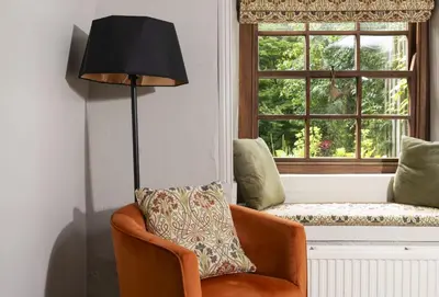 a living room with a chair and a window at The Corner Cottage in Camborne