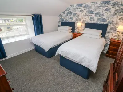 two beds in a small room with a window at The Old Post Office in Camborne