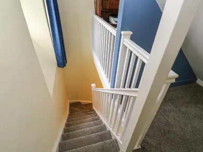 a staircase with blue walls and white railings at The Old Post Office in Camborne