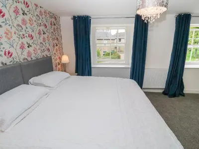 a bedroom with a white bed with blue curtains and a chandelier at The Old Post Office in Camborne