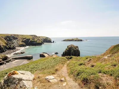 a dirt road leading to a beach near the ocean at The Old Post Office in Camborne