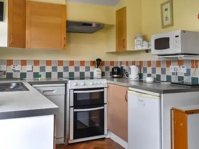 a kitchen with stainless steel appliances and wooden cabinets at Cat's Cove - Uk47720 in St Merryn