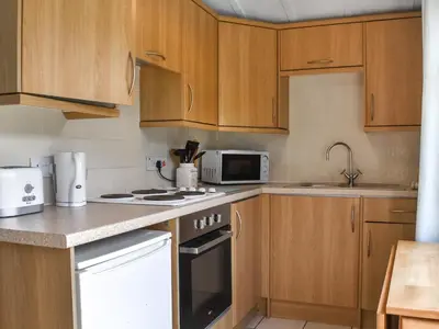 a kitchen with wooden cabinets and a stove top oven at Old Town Cove - Uk47724 in St Merryn