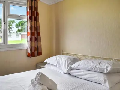 a bedroom with a bed with white sheets and a window at Harbour Cove - Uk47722 in St Merryn